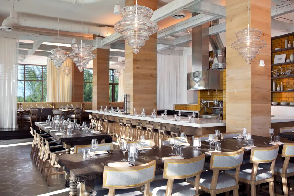 Bright dining room with long tables and pendant lights at Kimpton Seafire Resort + Spa