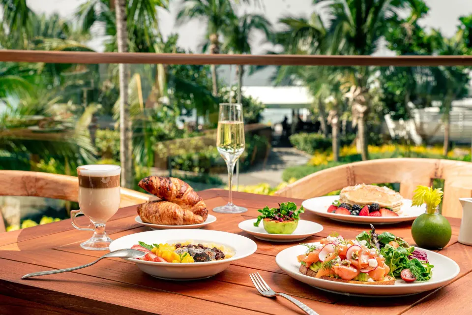 Outdoor breakfast spread on a balcony with palm trees at Kimpton Seafire Resort + Spa