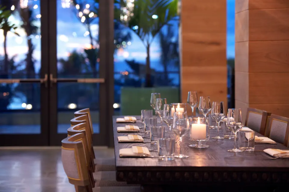 Evening table set with glassware and candlelight in a dining room at Kimpton Seafire Resort + Spa