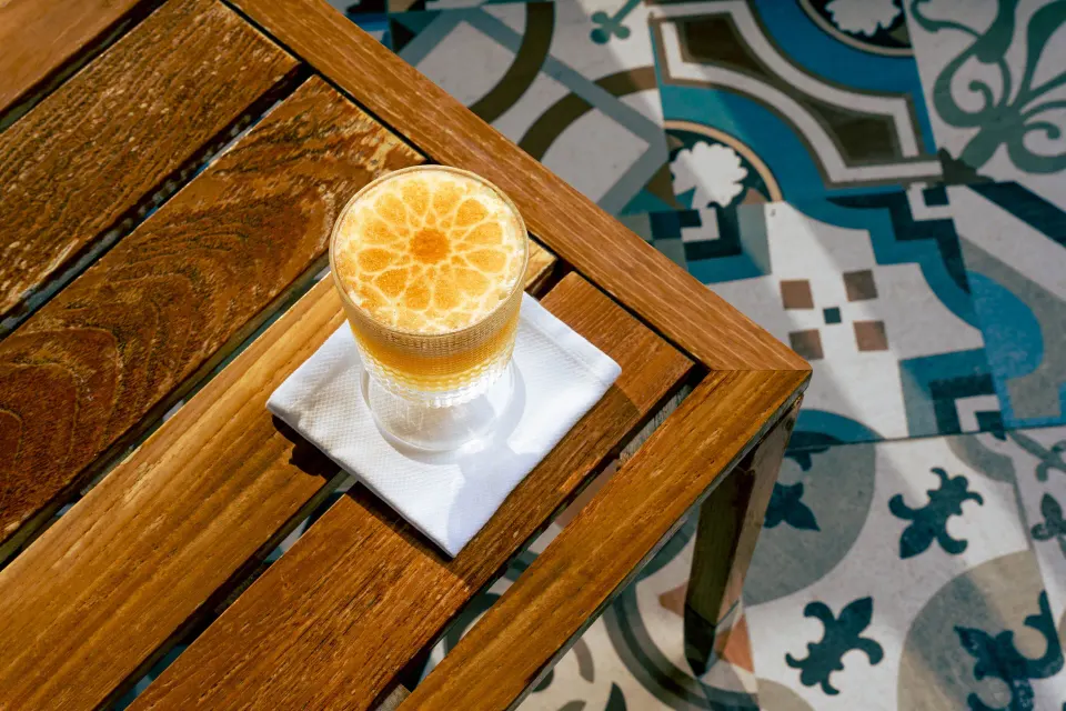 Cocktail glass on a wooden table with patterned tile floor at Kimpton Seafire Resort + Spa