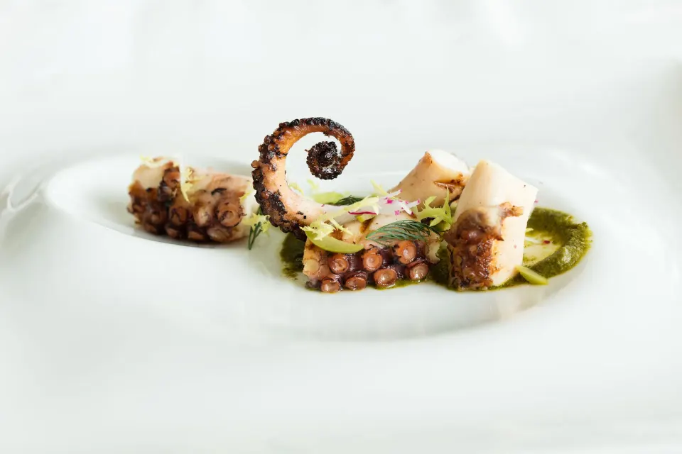 Grilled octopus with sauce on a white plate at Kimpton Seafire Resort + Spa