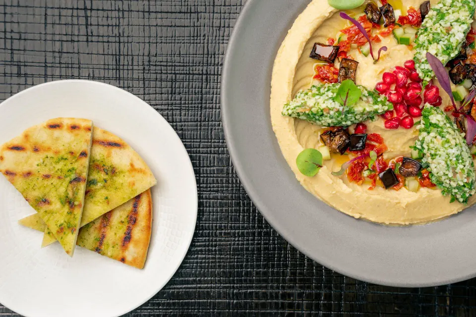 Plated hummus with garnishes and a side flatbread at Kimpton Seafire Resort + Spa