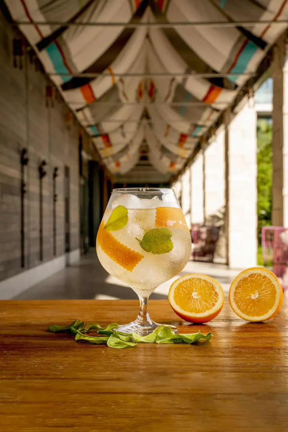 Large stemmed cocktail with citrus and herbs on a bar surface at Kimpton Seafire Resort + Spa