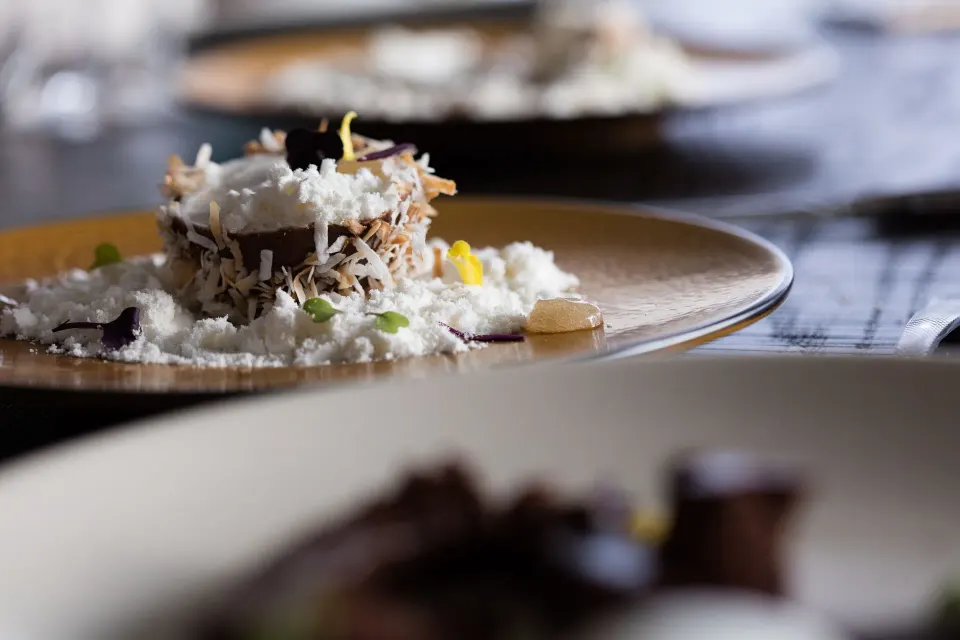 Close-up of plated dessert with coconut flakes and delicate garnishes at Kimpton Seafire Resort + Spa