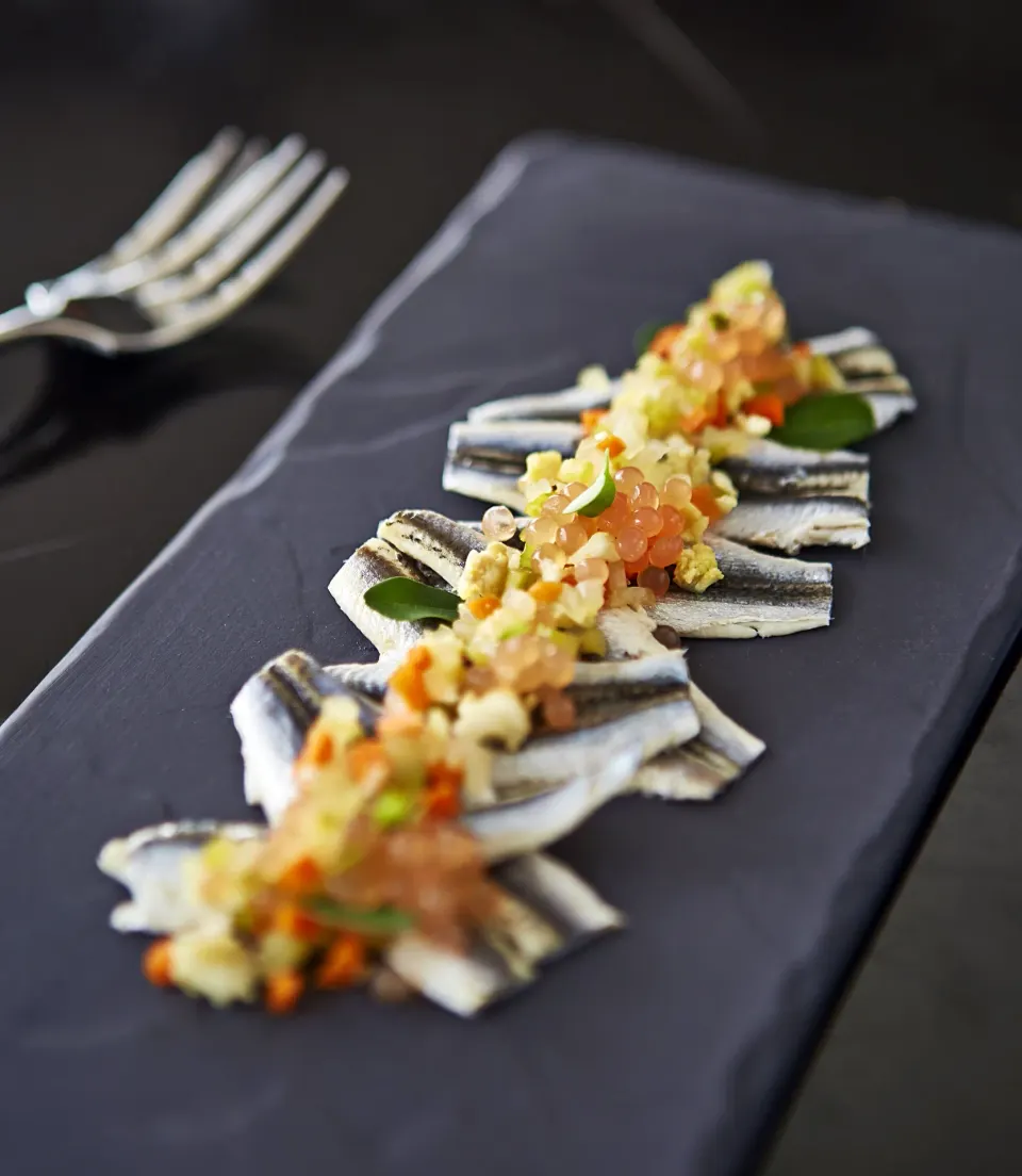 Plated seafood appetizer on a black rectangular slate at Kimpton Seafire Resort + Spa
