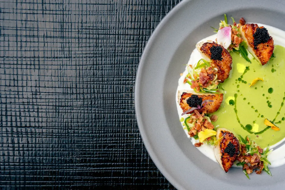 Seared scallops with green sauce and garnishes at Kimpton Seafire Resort + Spa