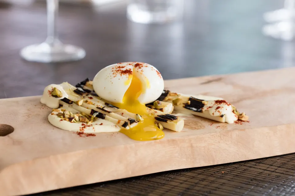 Soft-boiled egg with creamy sauce and pistachios on a wooden board at Kimpton Seafire Resort + Spa