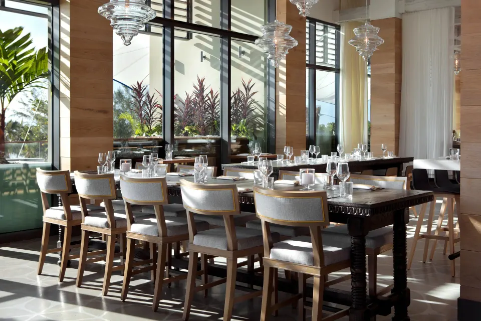 Sunlit dining room with long table and glass pendants at Kimpton Seafire Resort + Spa
