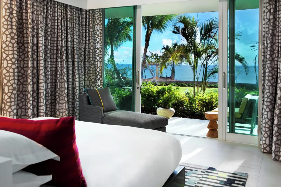 Bed and chaise lounge opening to a patio and ocean view at Kimpton Seafire Resort + Spa