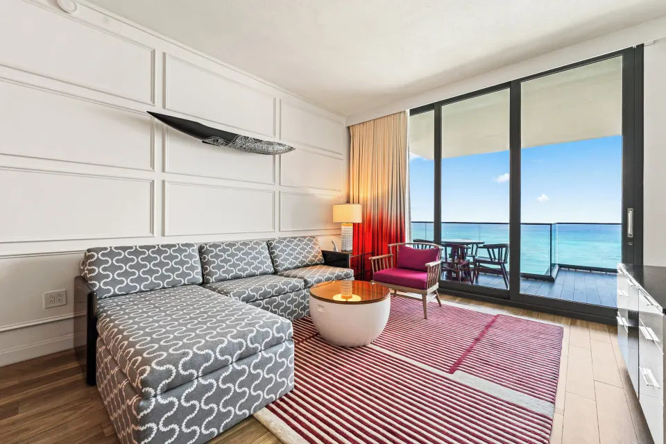 Living area with sectional sofa and balcony overlooking the ocean in an Oceanfront One-Bedroom Suite at Kimpton Seafire Resor