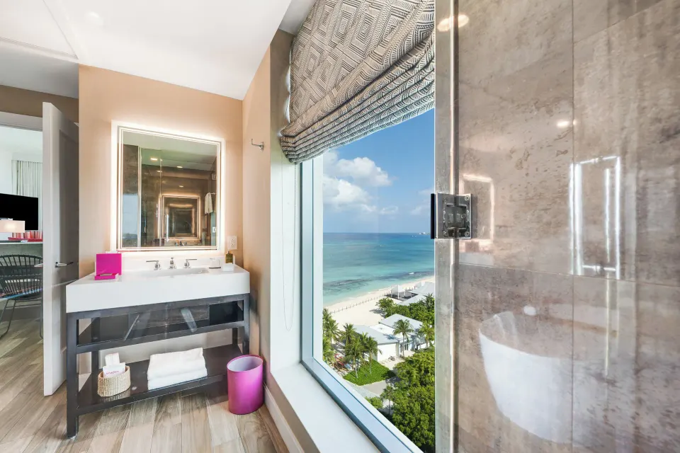 Vanity and shower beside ocean-facing window in Oceanfront One-Bedroom Suite at Kimpton Seafire Resort + Spa