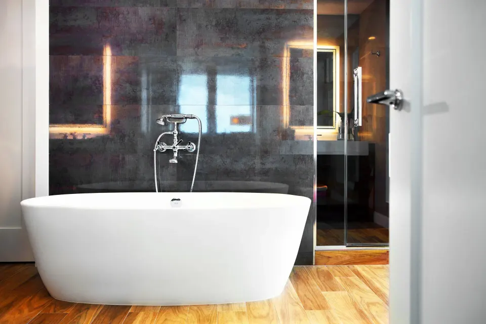 Freestanding tub framed by dark tile wall and shower in Oceanfront One-Bedroom Suite at Kimpton Seafire Resort + Spa