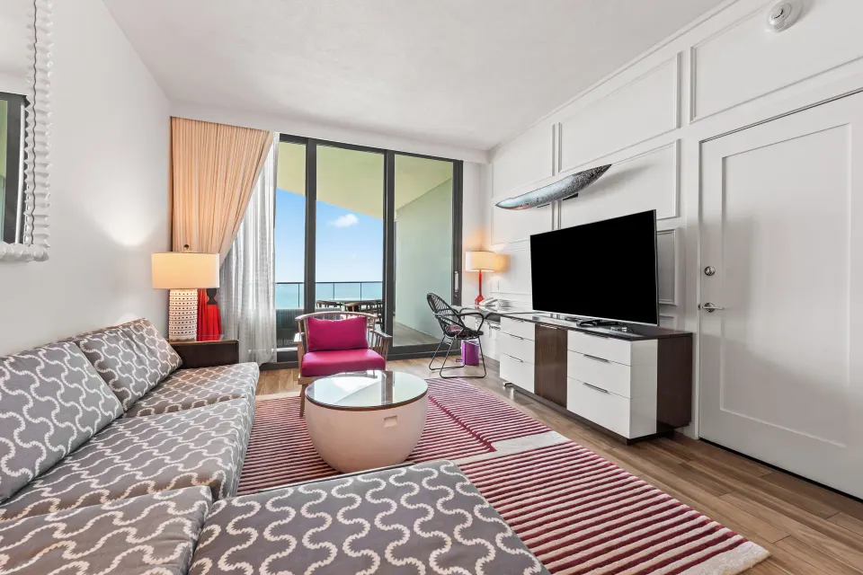 Seating area with sofa, TV and balcony ocean view in an Oceanfront One-Bedroom Suite at Kimpton Seafire Resort + Spa