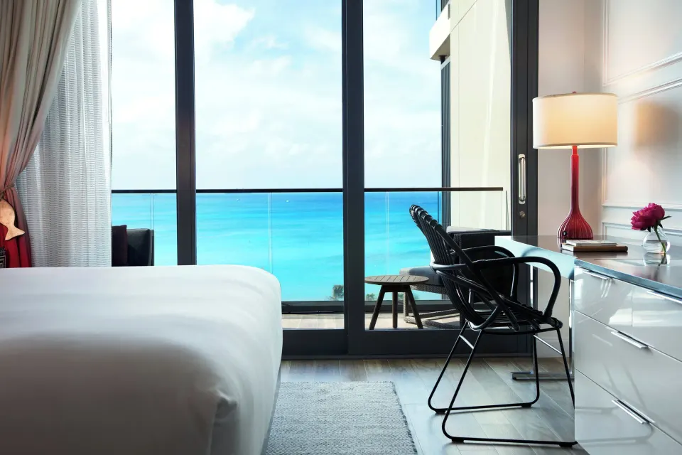 Bed and desk by floor-to-ceiling windows with ocean view at Kimpton Seafire Resort + Spa