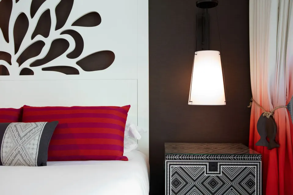 Close-up of bed pillows, bedside lamp and patterned nightstand at Kimpton Seafire Resort + Spa