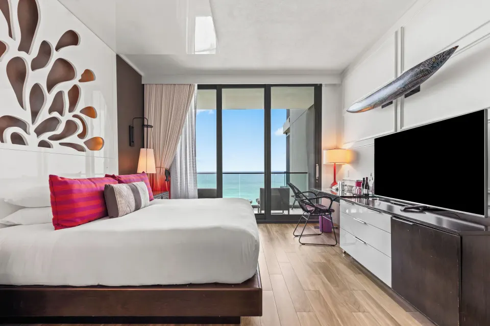 King bed, dresser and balcony door with ocean view in studio room at Kimpton Seafire Resort + Spa