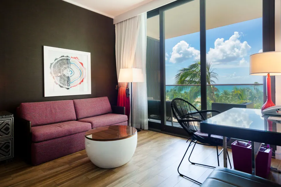Sofa and desk near balcony with palm-tree ocean view at Kimpton Seafire Resort + Spa