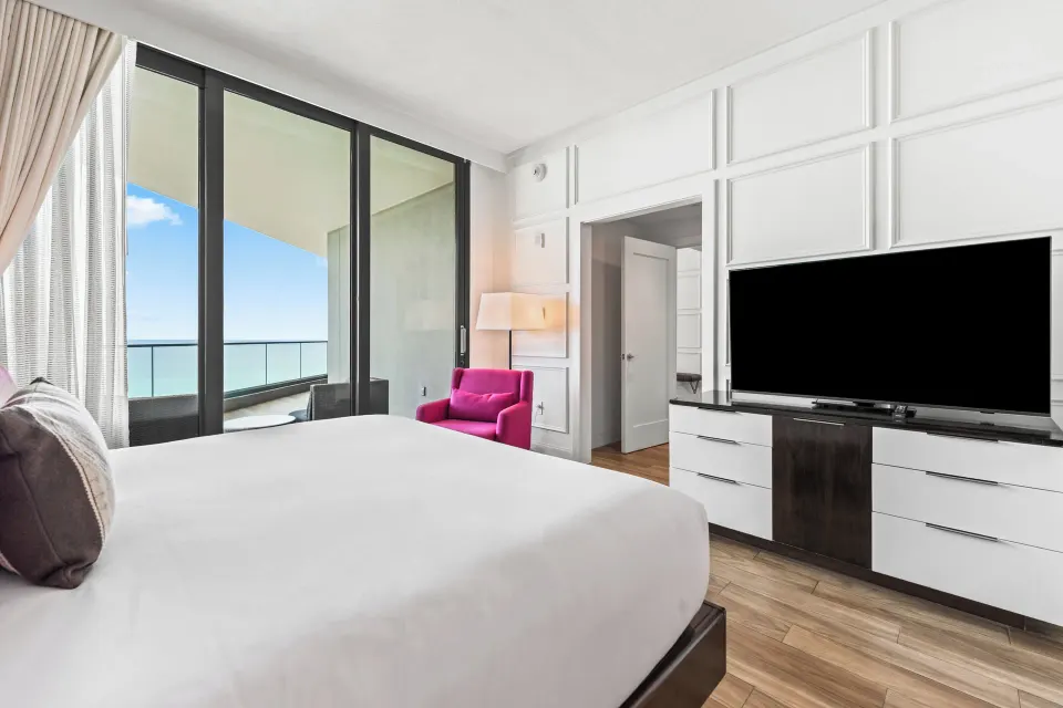 Television, dresser and balcony view from the bed in a Premium Ocean View One-Bedroom Family Suite at Kimpton Seafire Resort 
