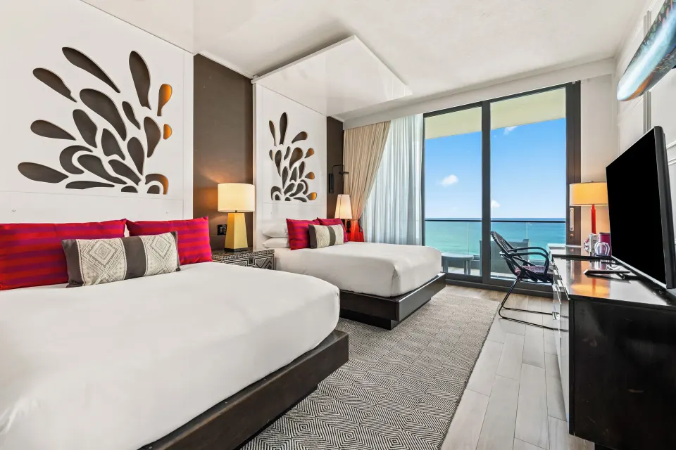 Two queen beds, TV console and balcony with ocean in a Premium Ocean View Queen Room at Kimpton Seafire Resort + Spa