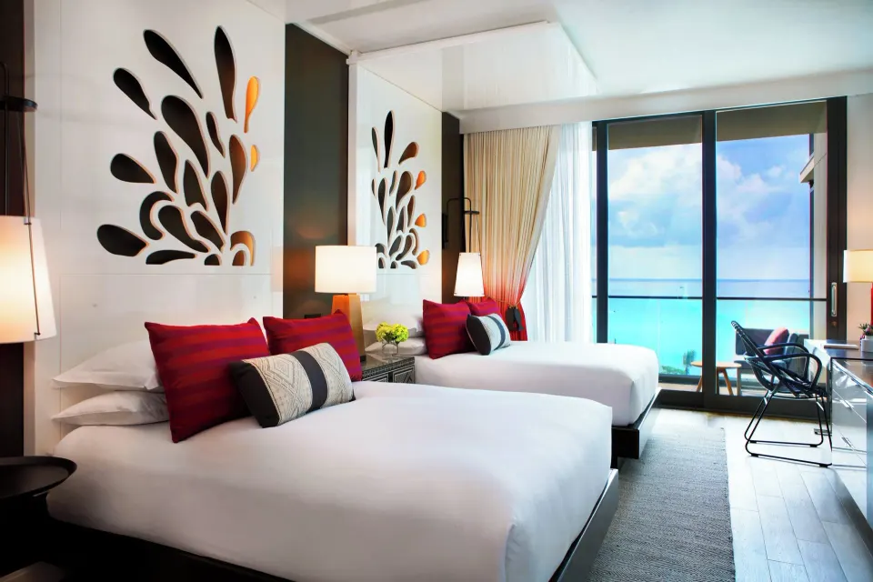 Interior view of a Premium Ocean View Queen Studio featuring two beds and ocean-facing balcony at Kimpton Seafire Resort + Sp