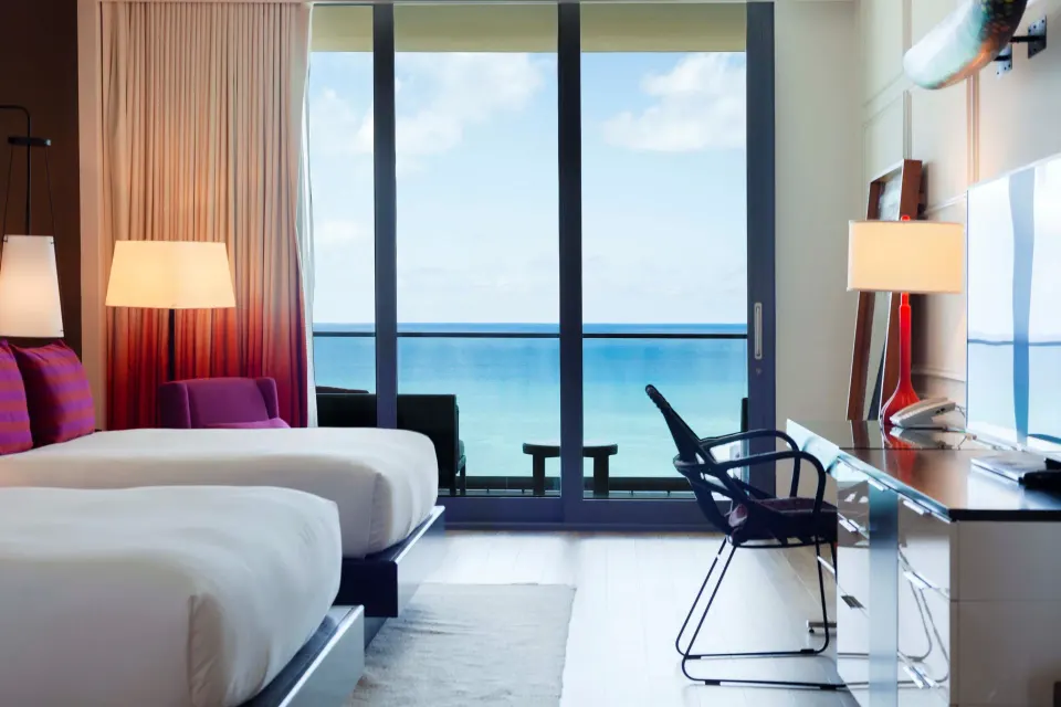 Two beds and balcony doors with ocean view in a Premium Oceanfront Room at Kimpton Seafire Resort + Spa