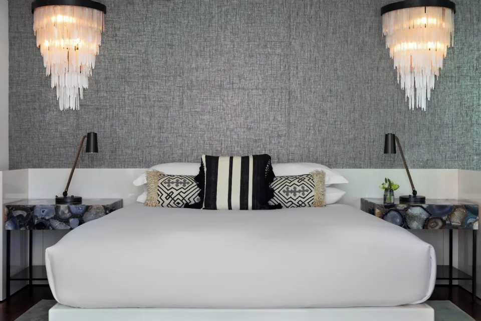 King bed with textured wall and pendant lights in a Presidential Oceanfront Two‑Bedroom Suite at Kimpton Seafire Resort + Spa
