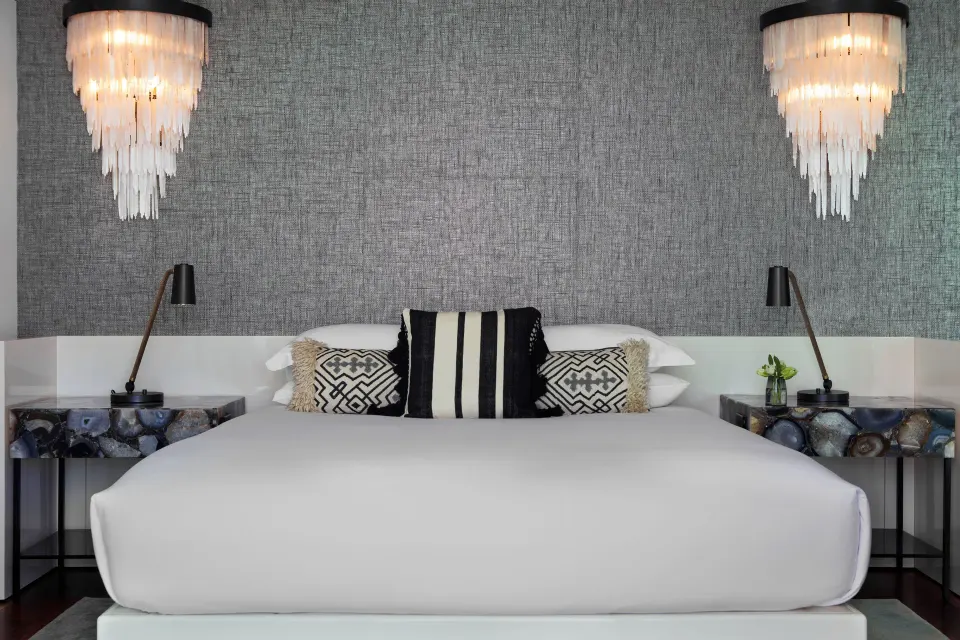King bed with textured wall and pendant lights in a Presidential Oceanfront Two‑Bedroom Suite at Kimpton Seafire Resort + Spa