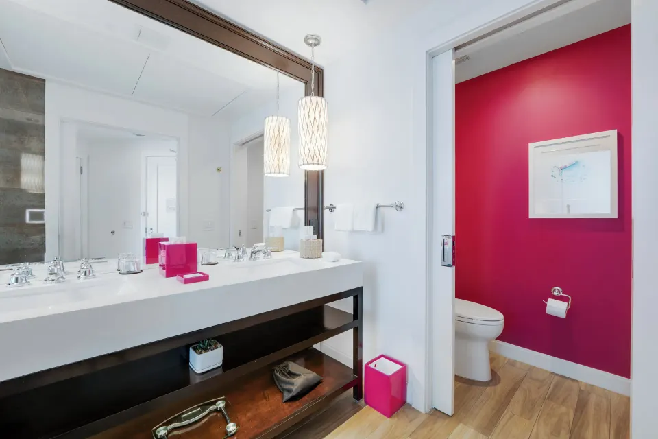 Close view of bathroom vanity and pink-walled toilet room in Yacht Club View King Room at Kimpton Seafire Resort + Spa