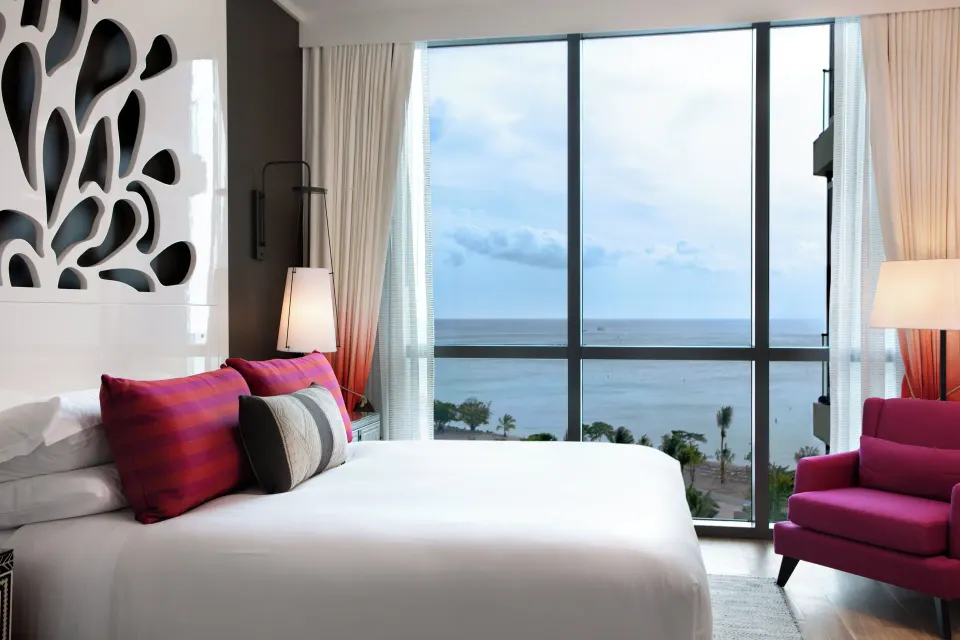 King bed with floor-to-ceiling windows showing ocean view in Yacht Club View King at Kimpton Seafire Resort + Spa