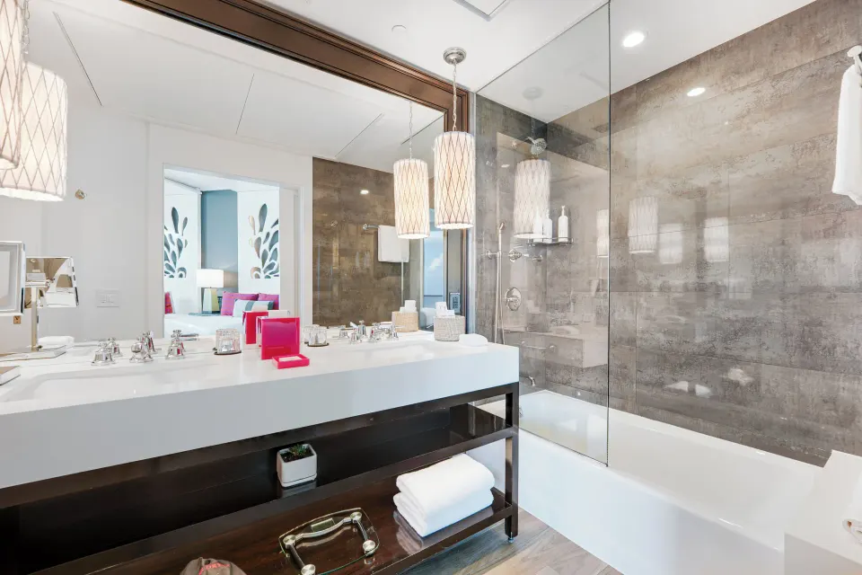 Guest bathroom with double sink vanity and glass-enclosed tub in Yacht Club View Room at Kimpton Seafire Resort + Spa