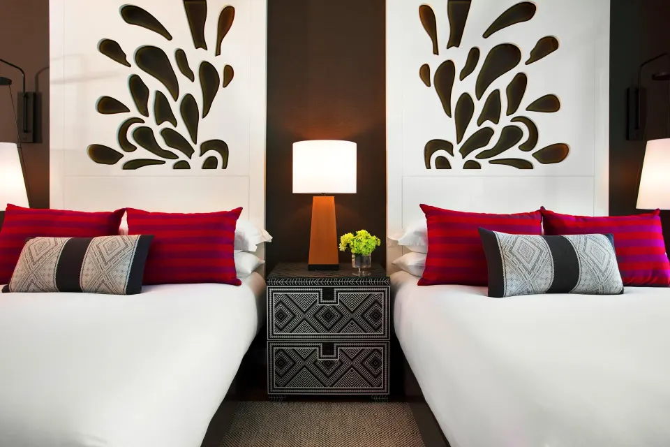 Close-up of twin beds with patterned pillows and central bedside table at Kimpton Seafire Resort + Spa