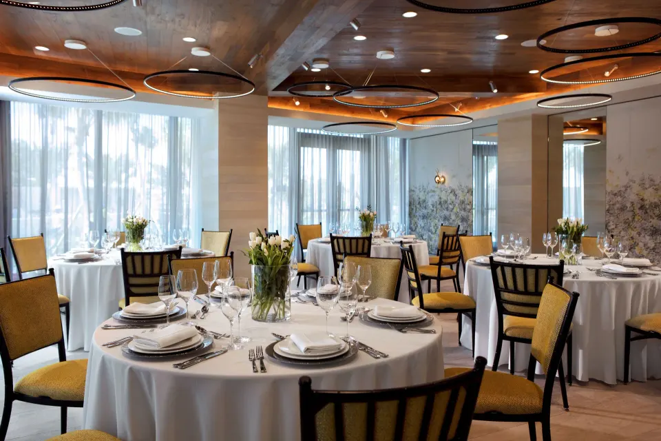 Round banquet tables set for a reception in a bright event room at Kimpton Seafire Resort + Spa