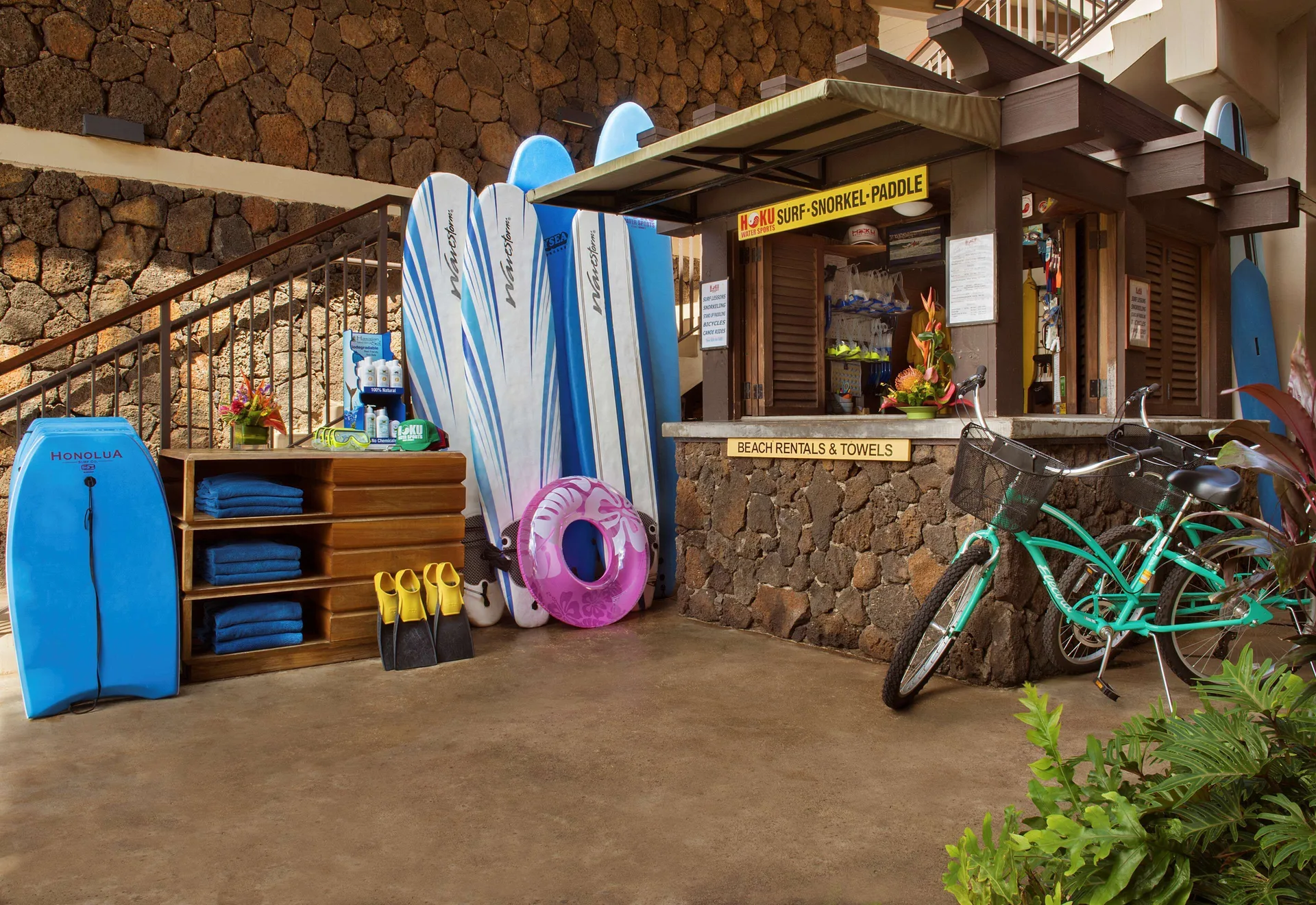 Beach rental stand at Ko'a Kea Resort on Po'ipu Beach with boards, fins, towels and a bicycle.