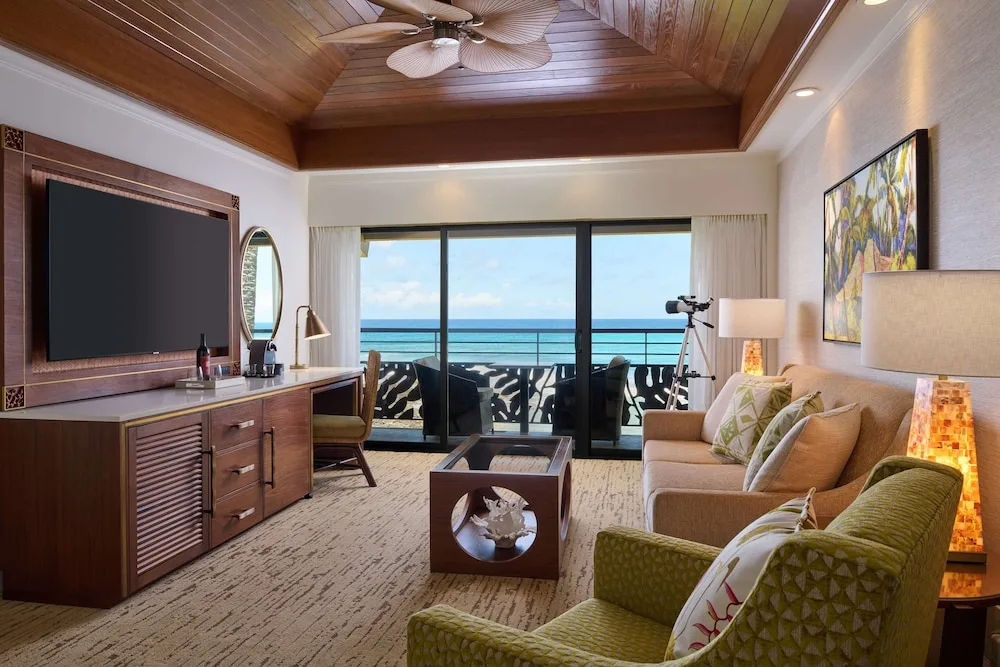Ocean-view living area with sofa, chairs, and balcony at Ko'a Kea Resort on Po'ipu Beach.