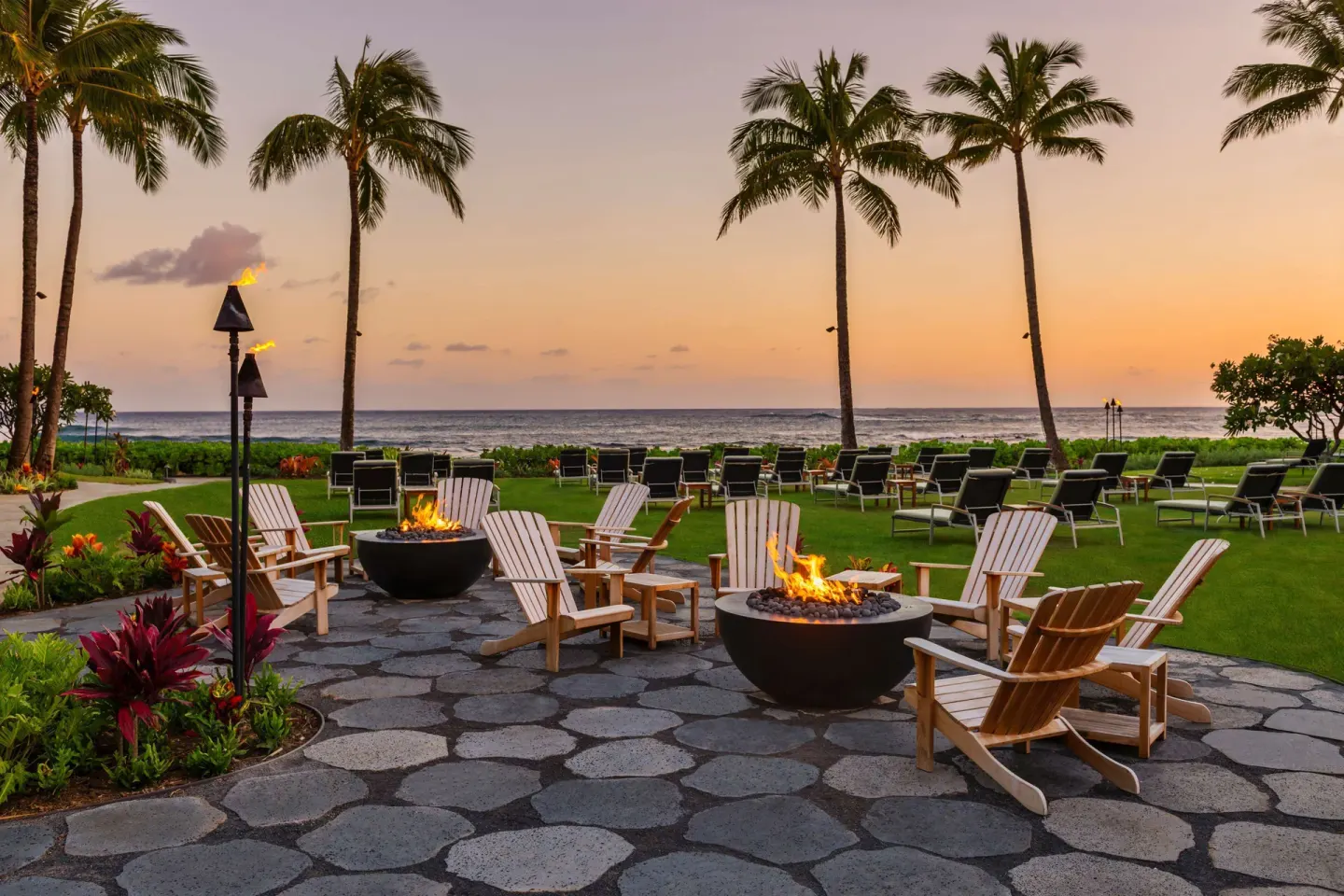 Oceanfront fire pits and lounge chairs at sunset at Ko'a Kea Resort on Po'ipu Beach.