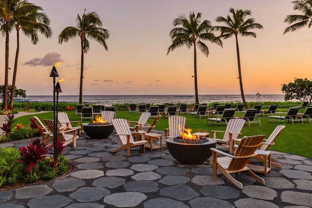Sunset lawn seating with fire pits and palms at Ko'a Kea Resort on Po'ipu Beach.