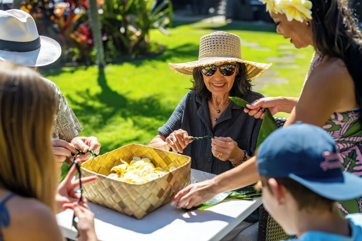 Guests weave flower lei outdoors at Ko'a Kea Resort on Po'ipu Beach.