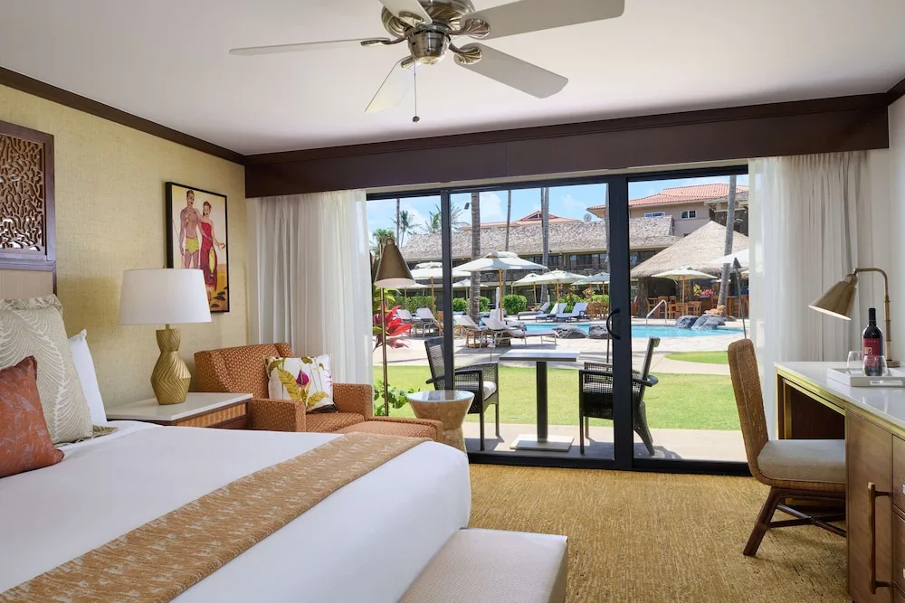 Guest room with one bed, patio, and pool view at Ko'a Kea Resort on Po'ipu Beach.