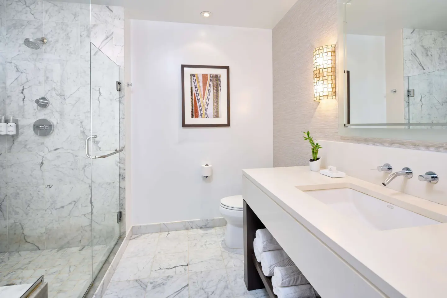 Guest room bathroom with glass shower and white vanity at Ko'a Kea Resort on Po'ipu Beach.