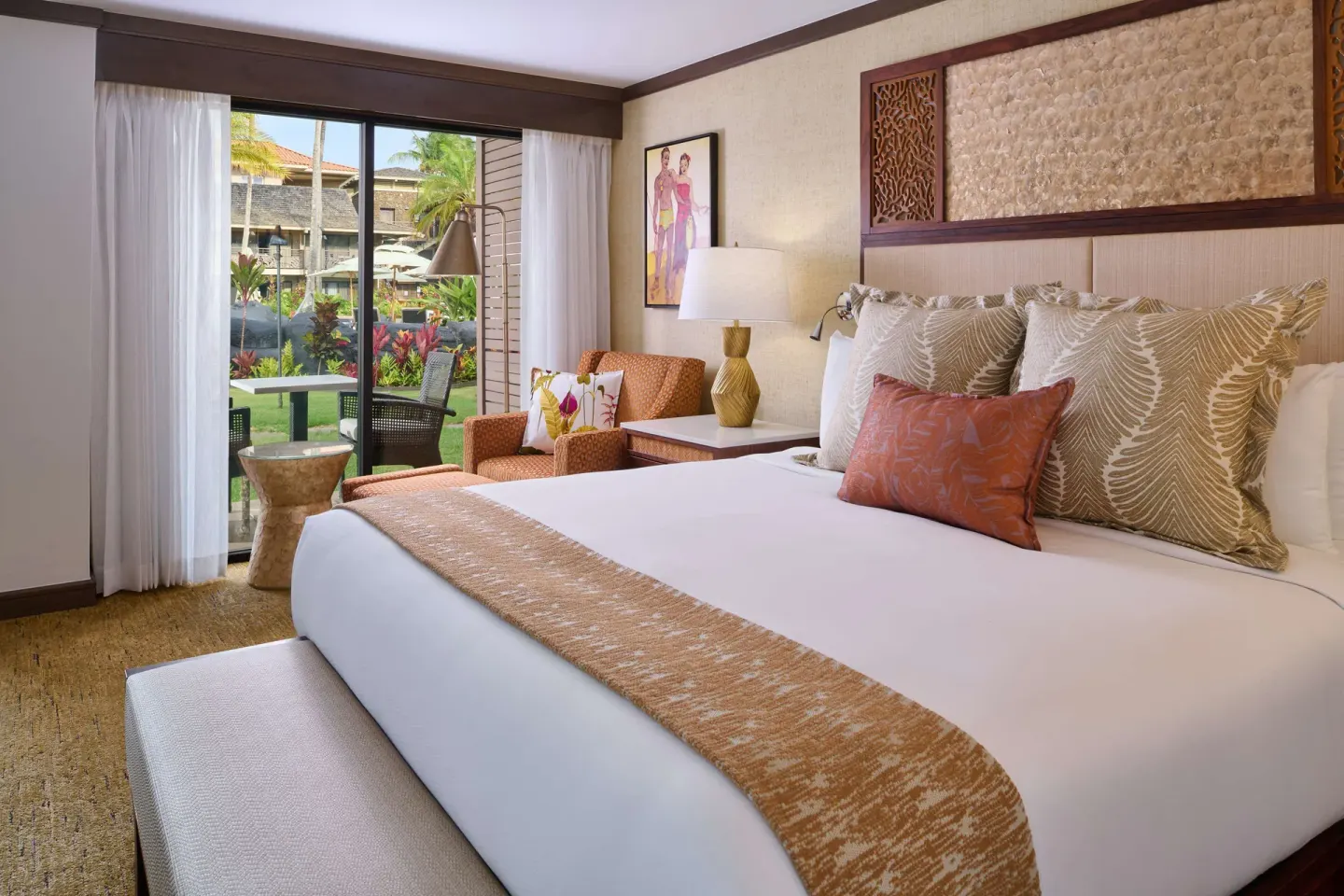 King bed with garden patio view in a guest room at Ko'a Kea Resort on Po'ipu Beach.