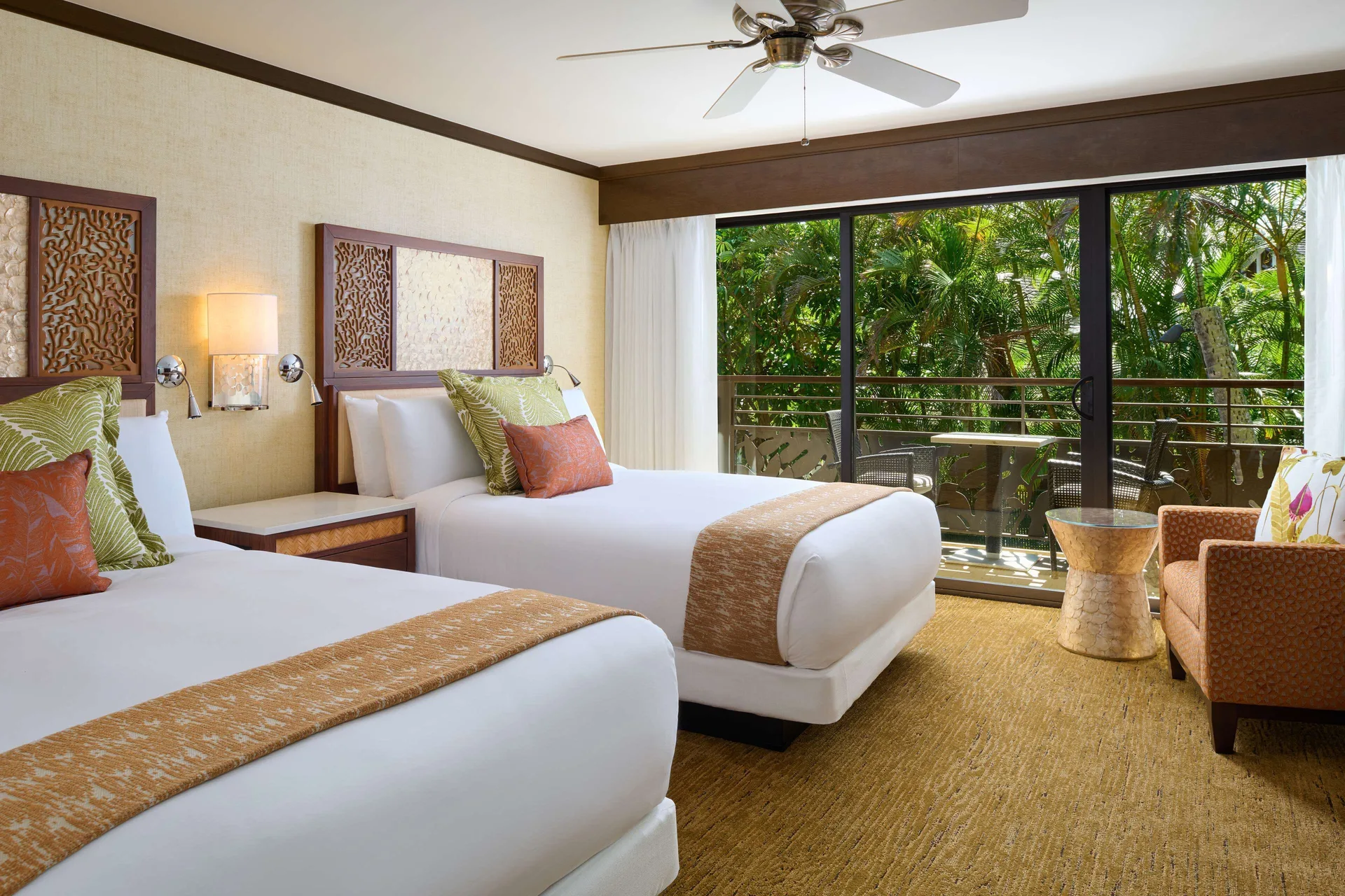 Two queen beds and a garden-facing balcony in a guest room at Ko'a Kea Resort on Po'ipu Beach.
