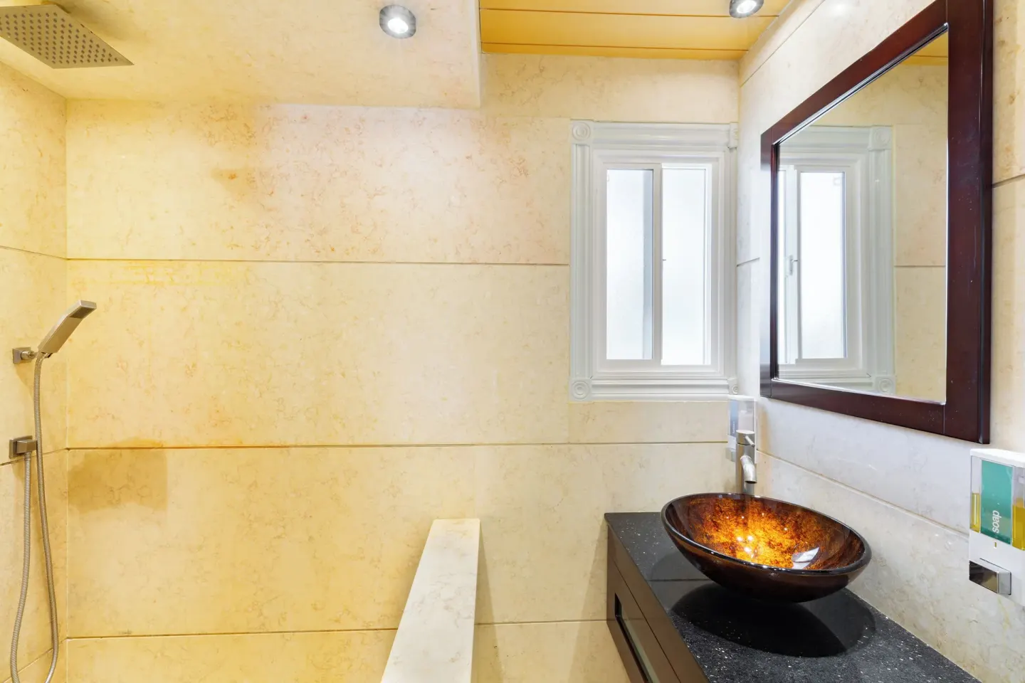 Bathroom with shower, small window, and vessel sink at Kokomo Botanical Resort.