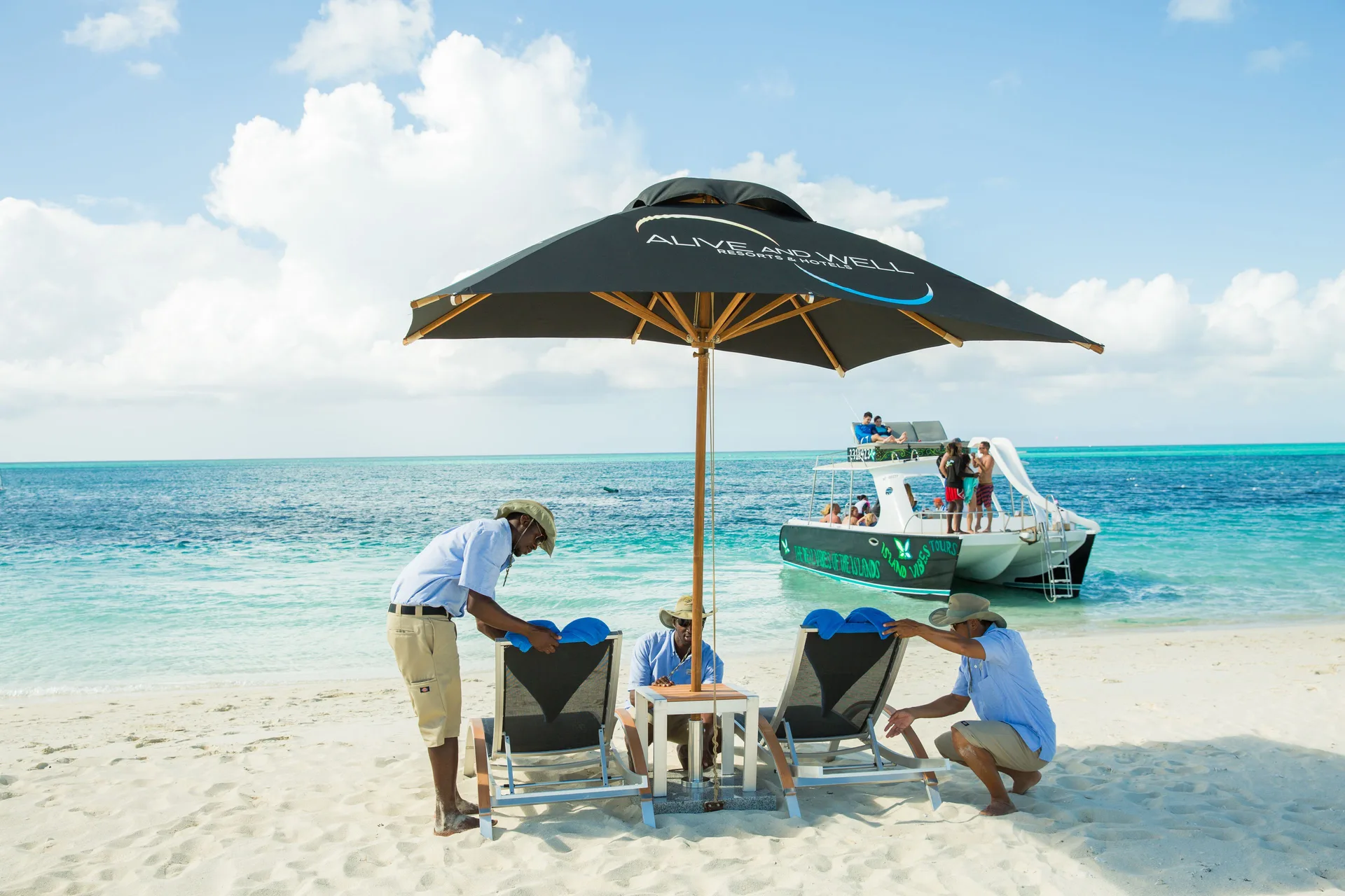 Beach chairs and an umbrella are set on white sand at Kokomo Botanical Resort.
