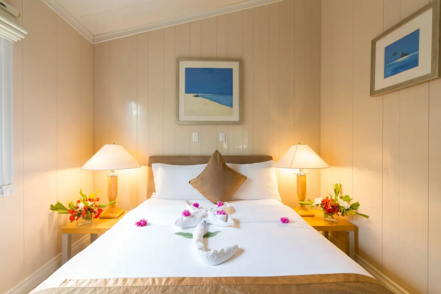 Guest room king bed with flowers on bedside tables at Kokomo Botanical Resort.
