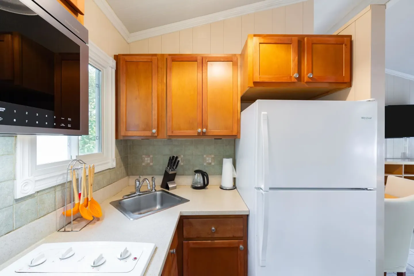 Small guest room kitchen with white refrigerator and wood cabinets at Kokomo Botanical Resort.