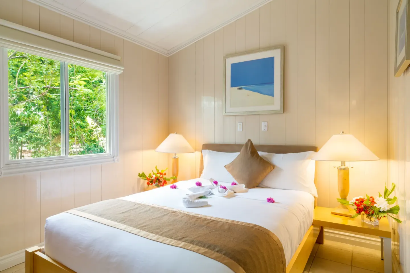 Guest room with a queen bed, lamps, and garden window at Kokomo Botanical Resort.