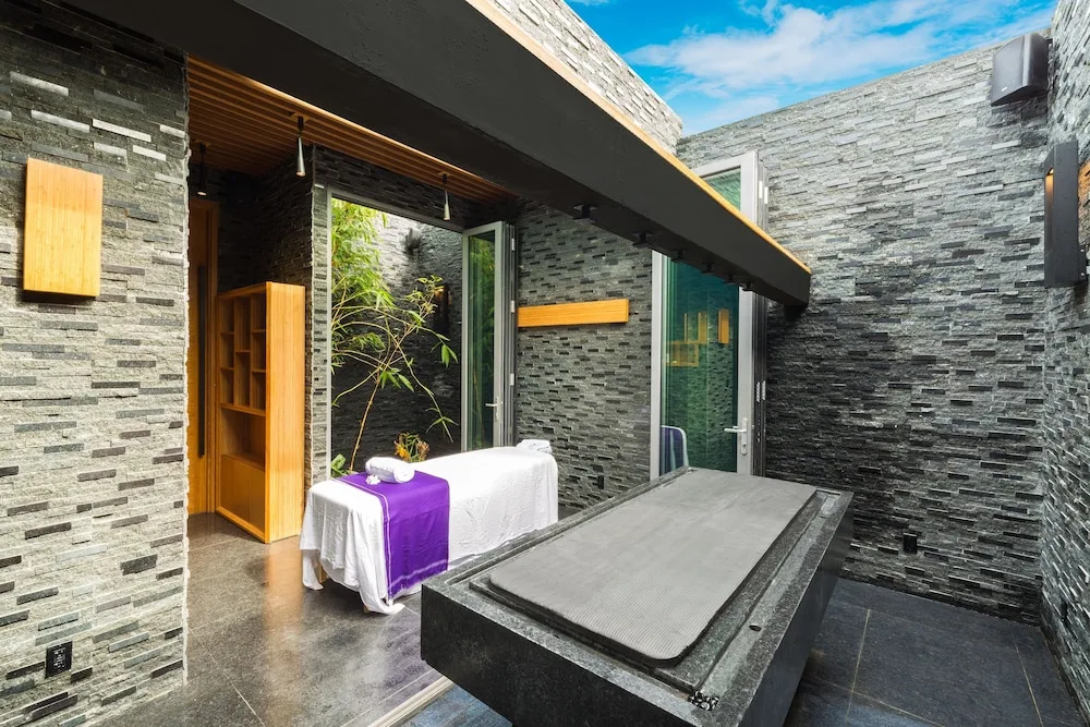 Open-air spa courtyard with treatment table and stone finishes at Kokomo Botanical Resort.