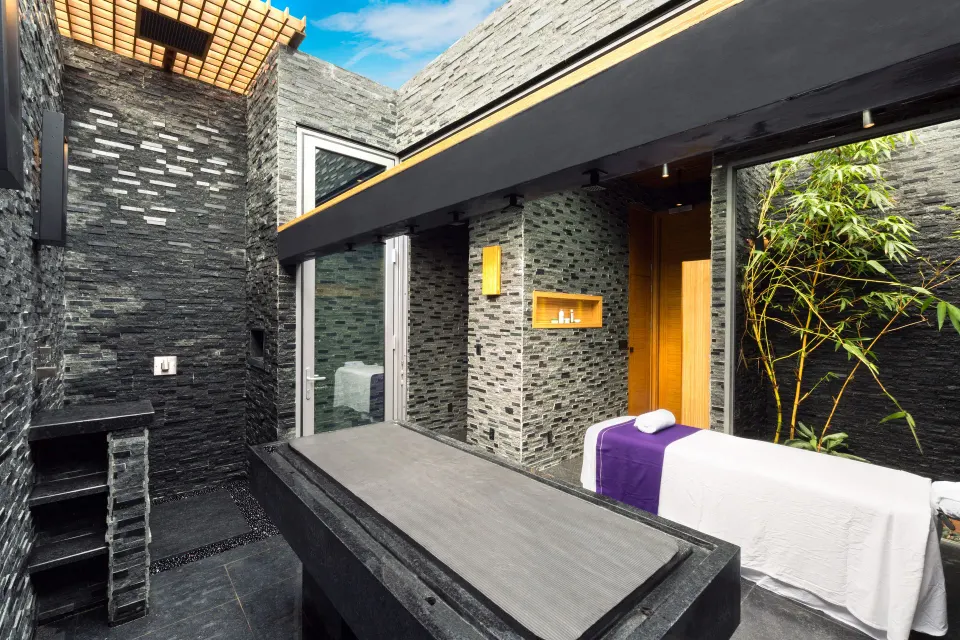 Private spa courtyard with treatment table and stone walls at Kokomo Botanical Resort.