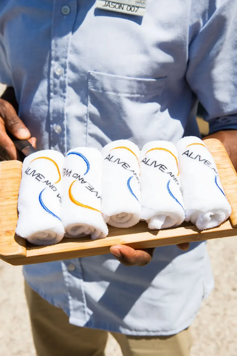Staff member holding rolled towels on a tray at Kokomo Botanical Resort.