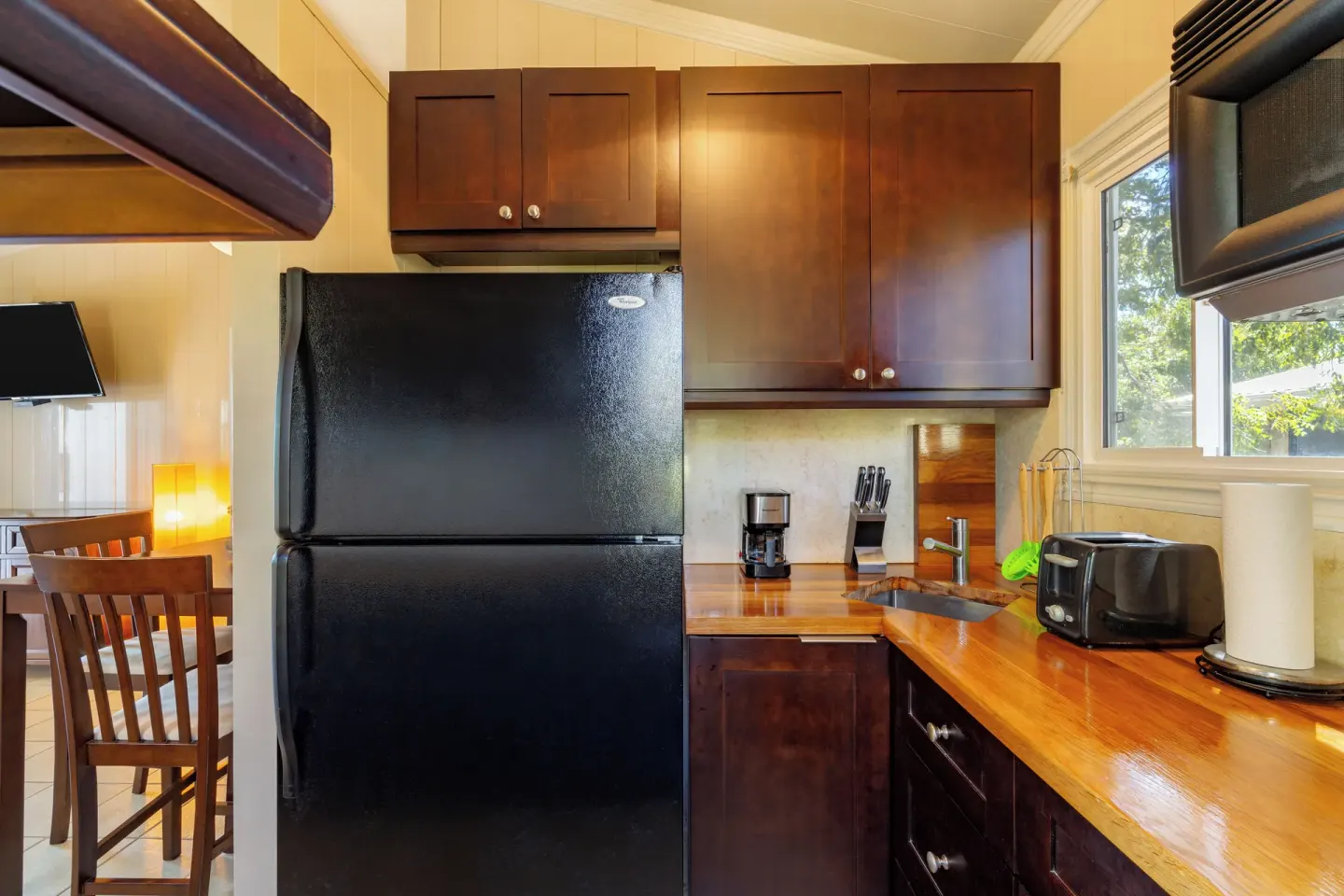 Compact suite kitchen with black refrigerator and wood counters at Kokomo Botanical Resort.